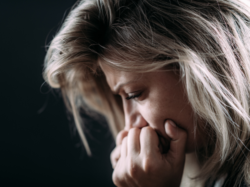 Woman sitting with head down: “person experiencing emotional overwhelm or trauma response”